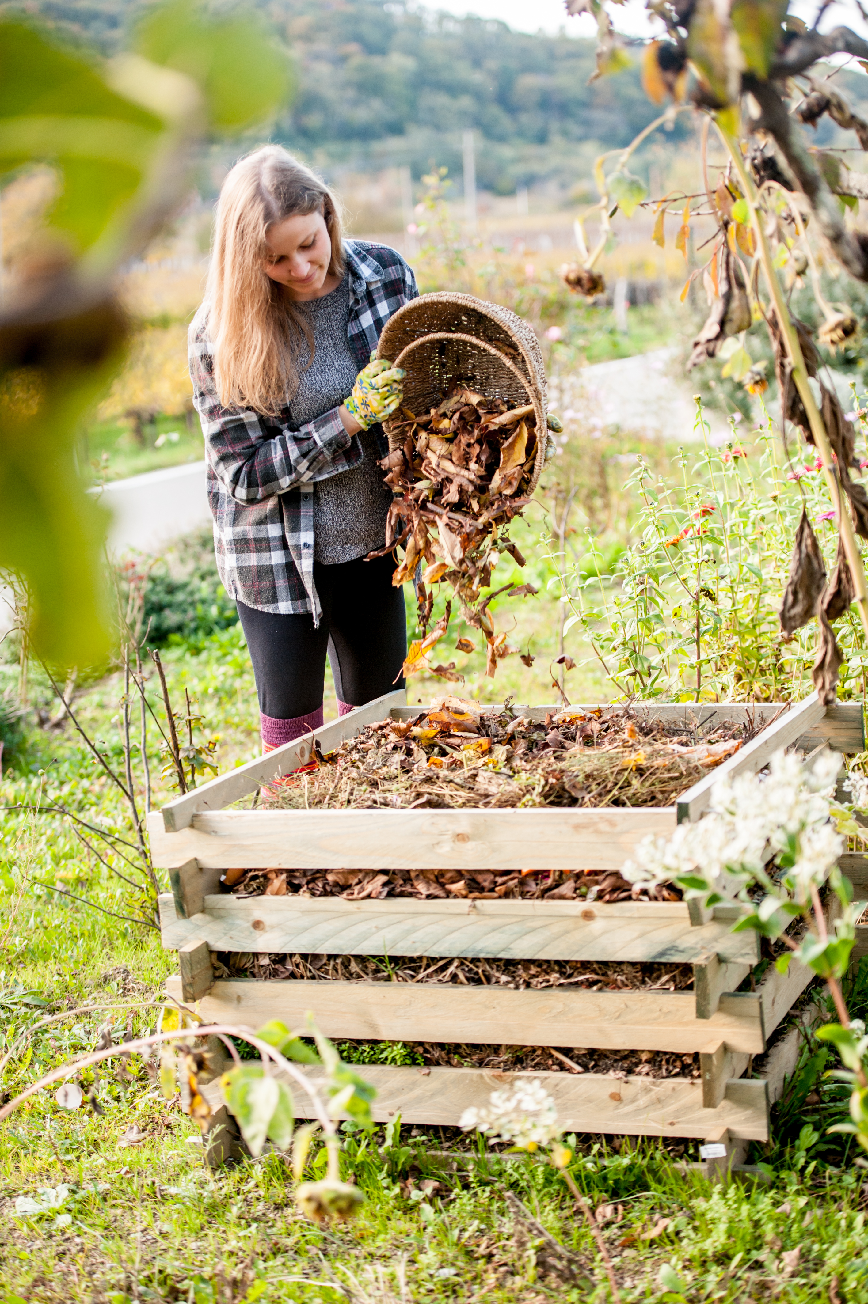 Young Woman Shaking Leaves Out of Basket to Compost